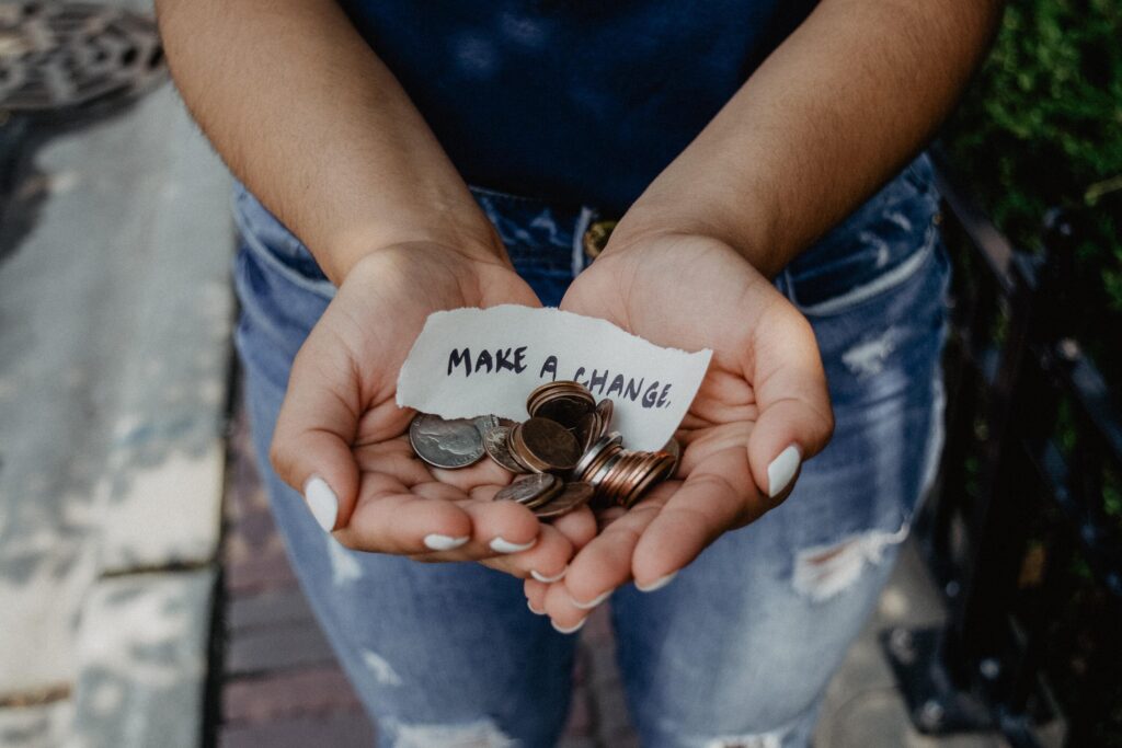 a pair of hands holds loose change and a note that says "make a change"