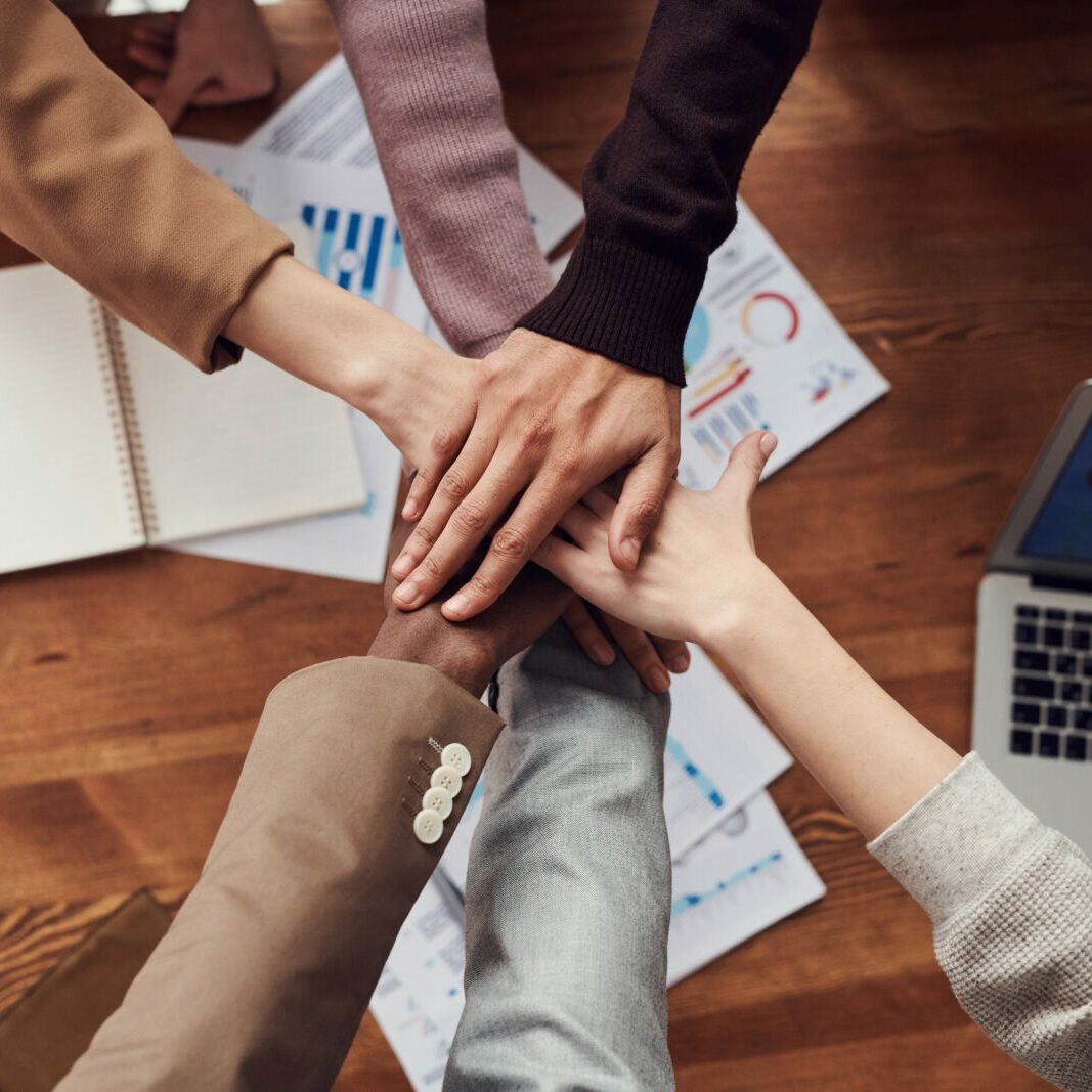 Diverse workers with hands stacked working together